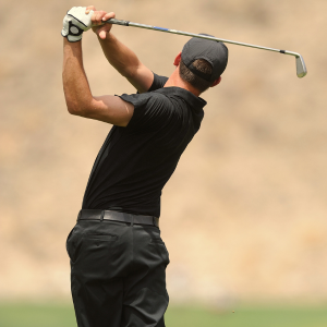 Golfer in black swinging a golf club on the course