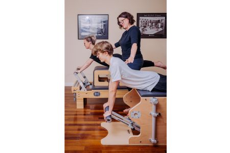 Woman teaching two students pilates on retainers